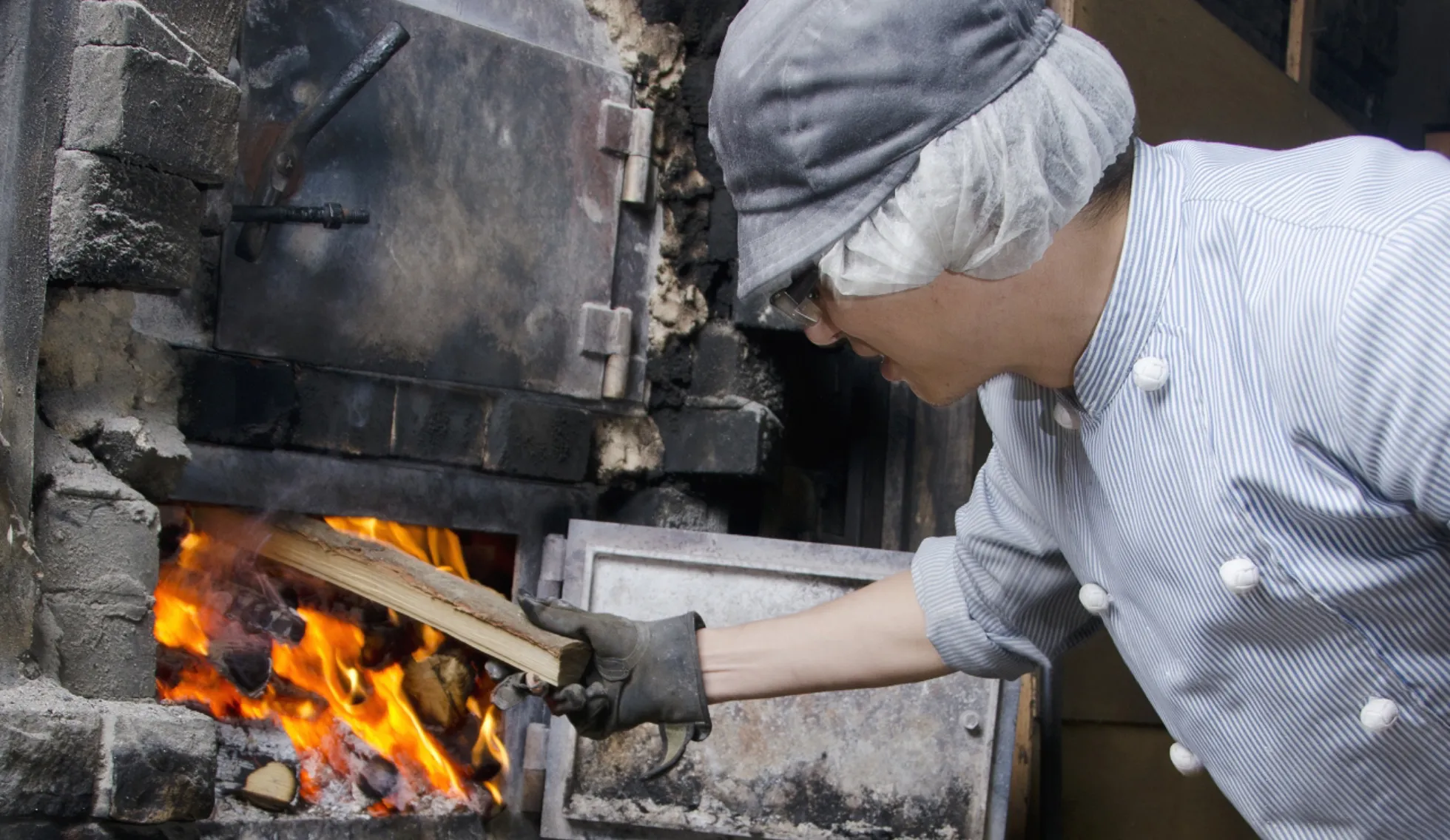 画像:炉に薪をくべる男性
